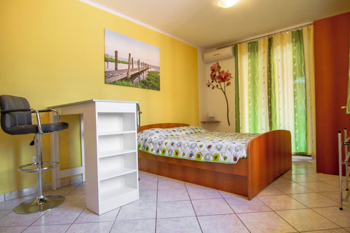 A bedroom with a bed, a chair, a wardrobe, and a picture on the wall.