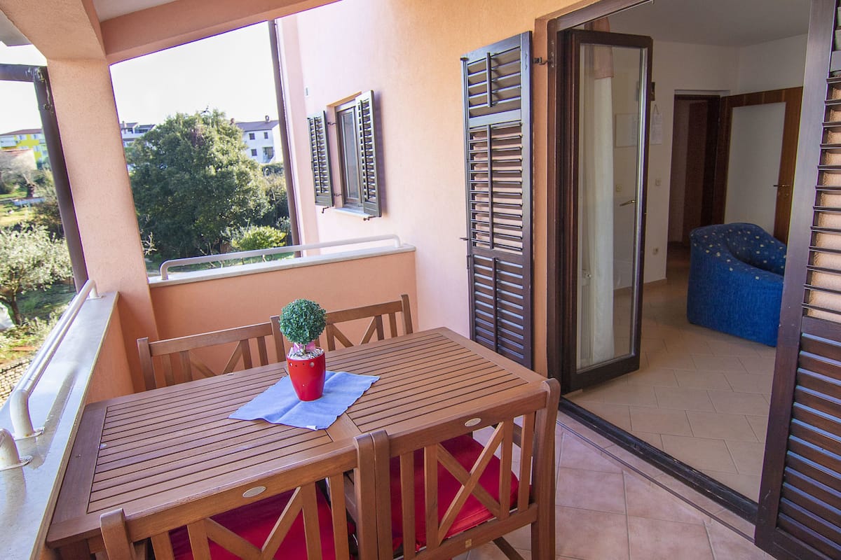 A wooden table with red cushions, a potted plant, and a view of a blue sofa and a door in the background.