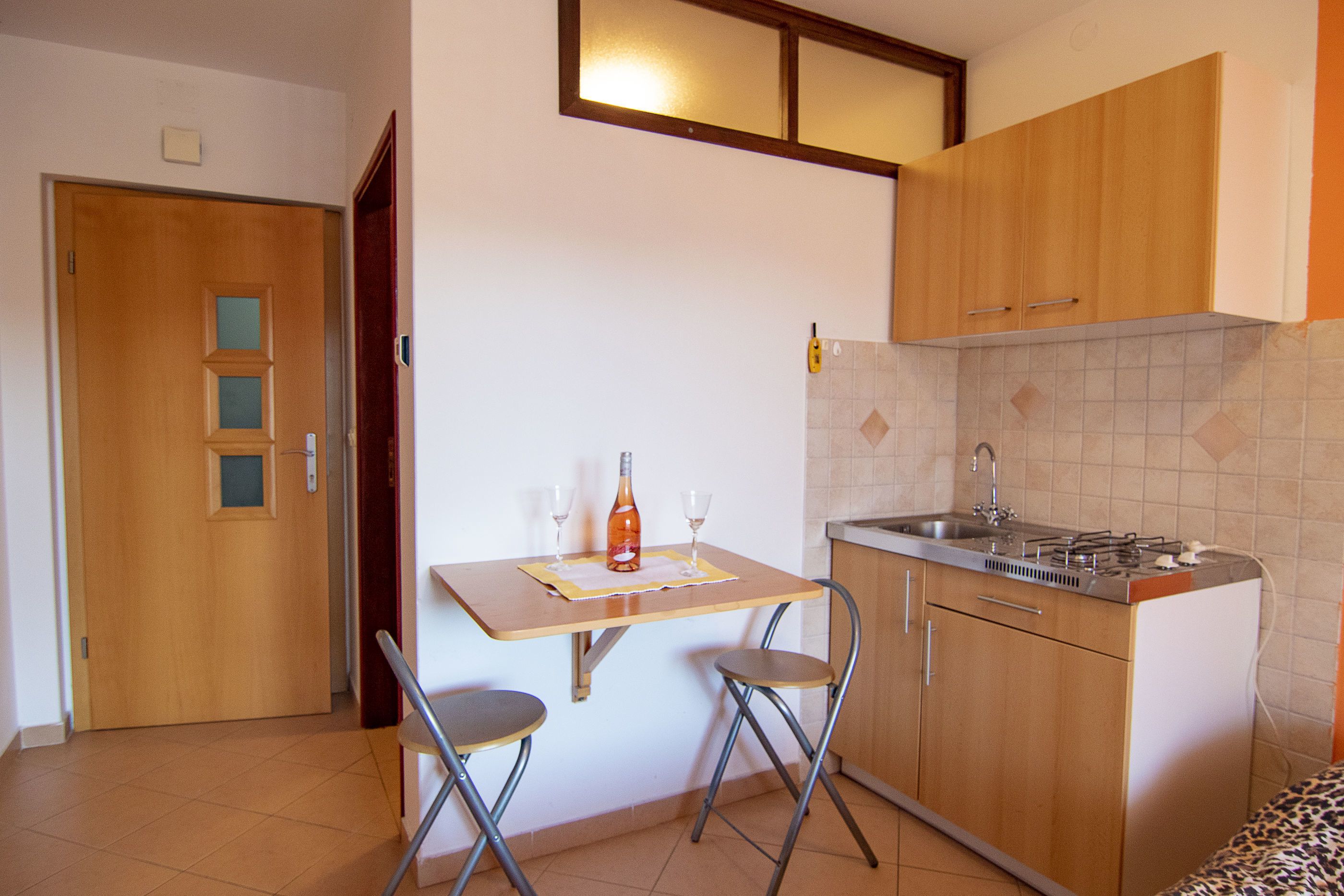 A compact kitchen with a wooden table, two chairs, a sink, and a stove.