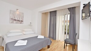Une chambre à coucher comprenant un lit, une chaise, un tableau et une porte coulissante donnant sur un balcon.
