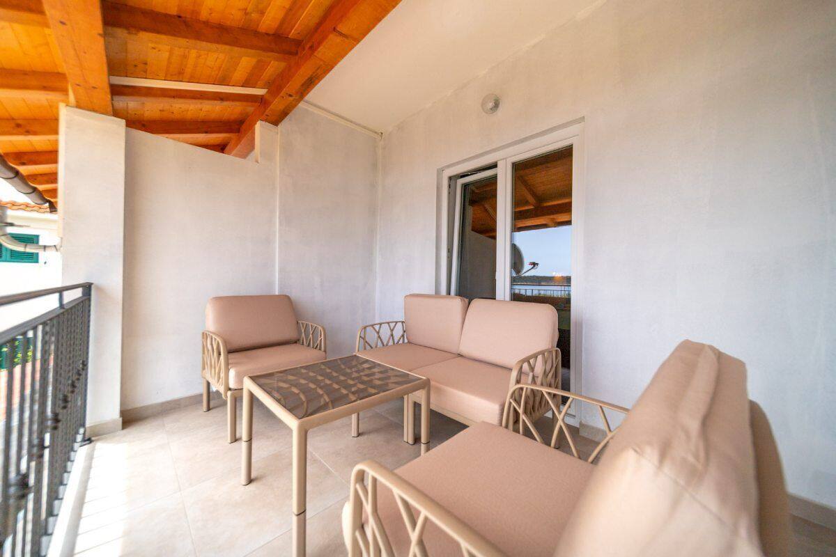 A balcony with a sofa, two chairs, and a table.