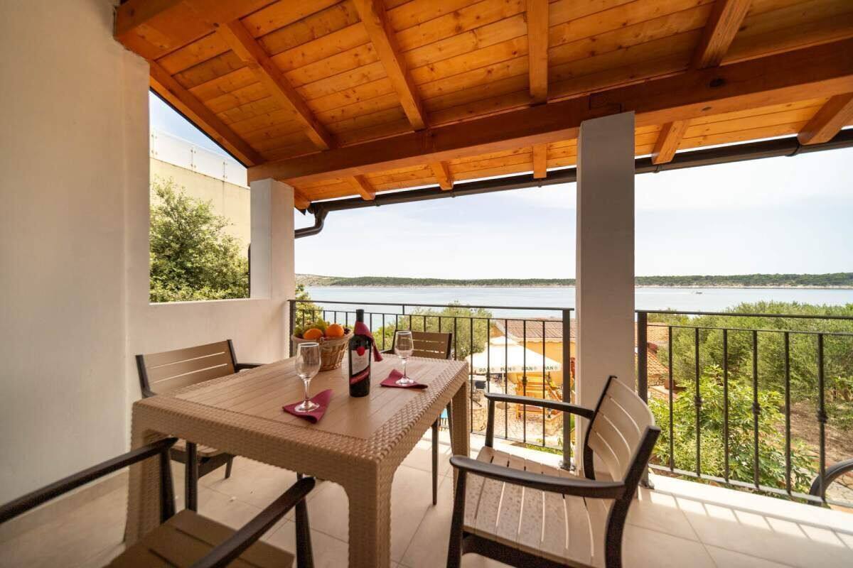A covered outdoor dining area with a table set for two, overlooking a body of water.