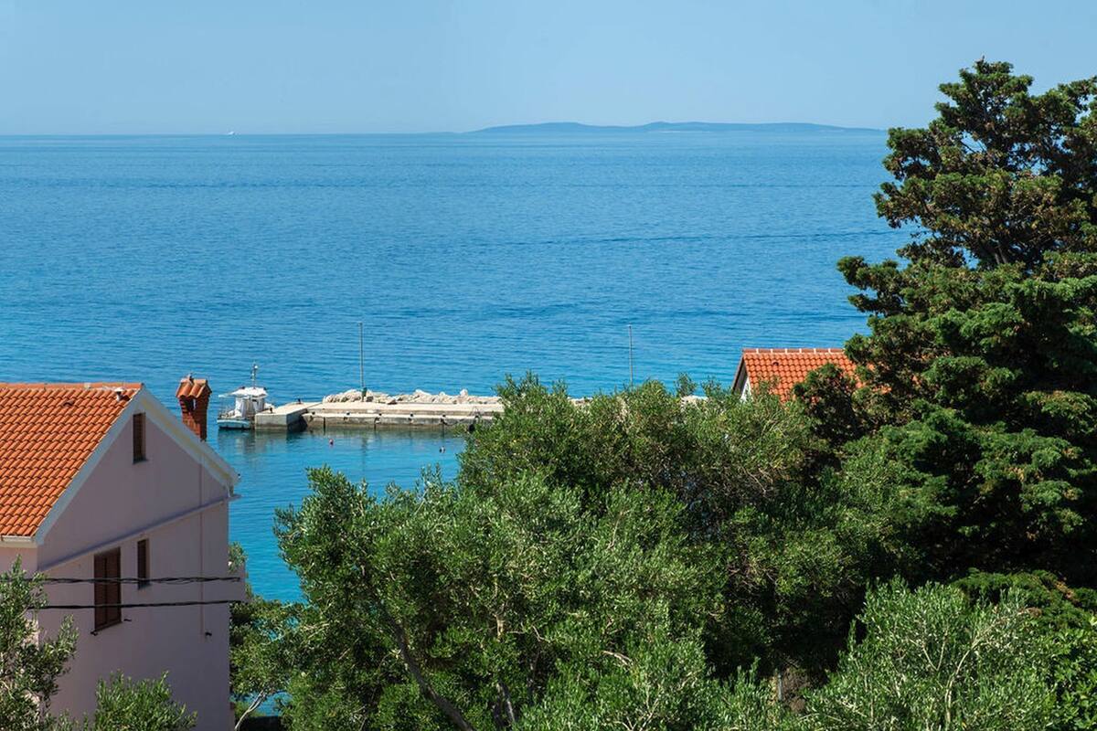 Une vue sur la côte, avec une jetée, des bâtiments aux toits rouges et une végétation luxuriante.
