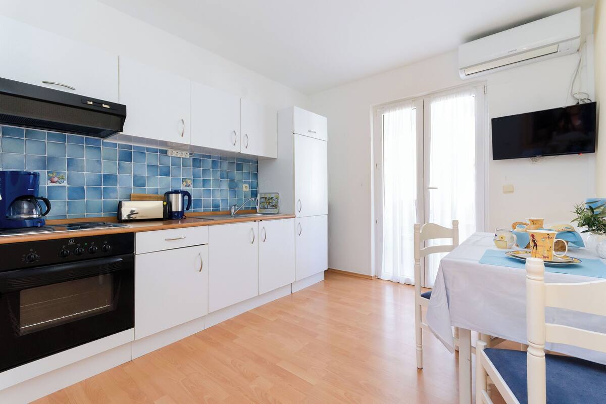 A modern kitchen with white cabinets, a black stove, and a blue tiled backsplash.
