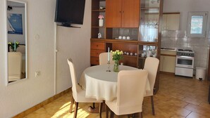 Un coin repas avec une table ronde, des chaises et un téléviseur fixé au mur.