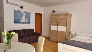Une chambre à coucher comprenant un lit, un canapé, une armoire, une table avec un vase de fleurs et un tableau accroché au mur.