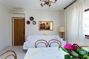 Une pièce comprenant un lit, une table à manger avec des chaises, un miroir et une fenêtre avec des rideaux.