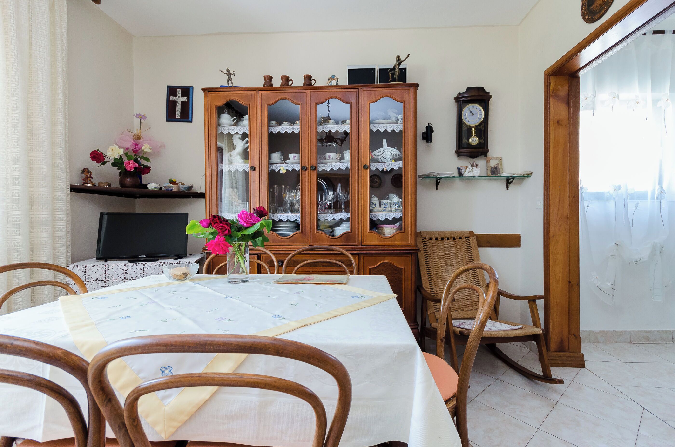 A dining area with a wooden cabinet, a television, and a table set for two.