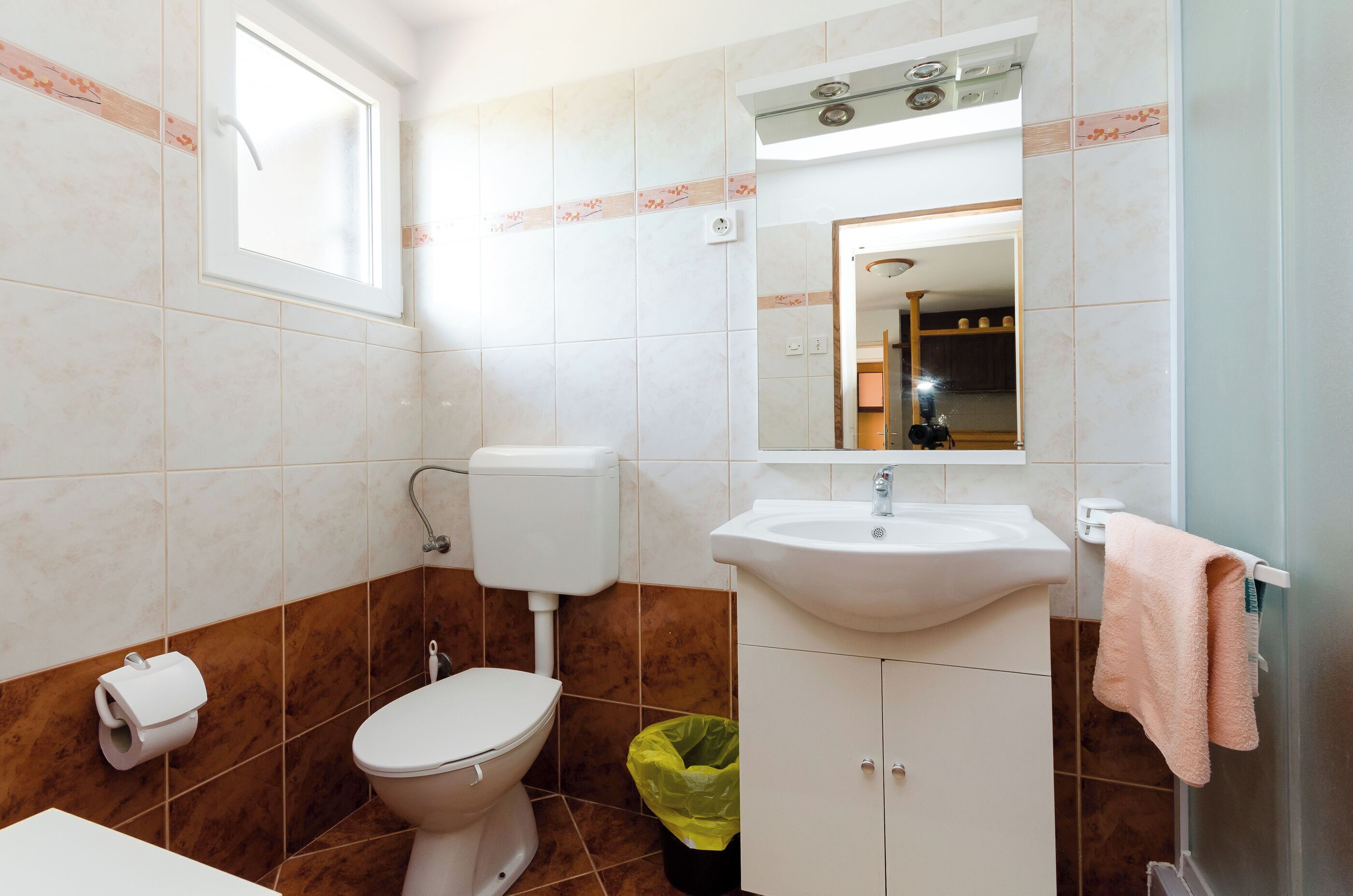 A bathroom with a toilet, sink, and window.