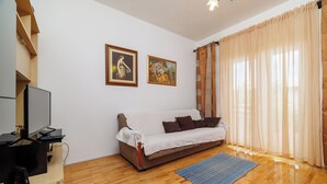 A living room with a sofa, a television, and two framed pictures on the wall.