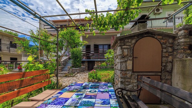 A courtyard with a tiled floor, a wooden bench, and a stone wall with a door.