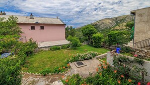 A pink building with a tiled roof, surrounded by a well-maintained garden with various plants and flowers.