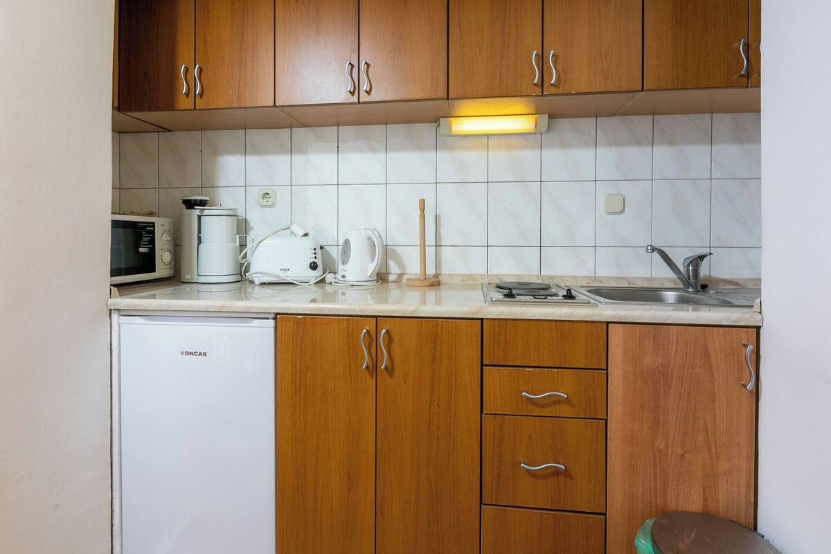 Eine kleine Küche mit Holzausstattung, einer Mikrowelle, einer Kaffeemaschine und einem Spülbecken.