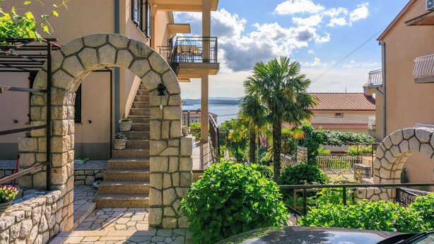 Una escalera de piedra que lleva a un balcón con vistas al mar.