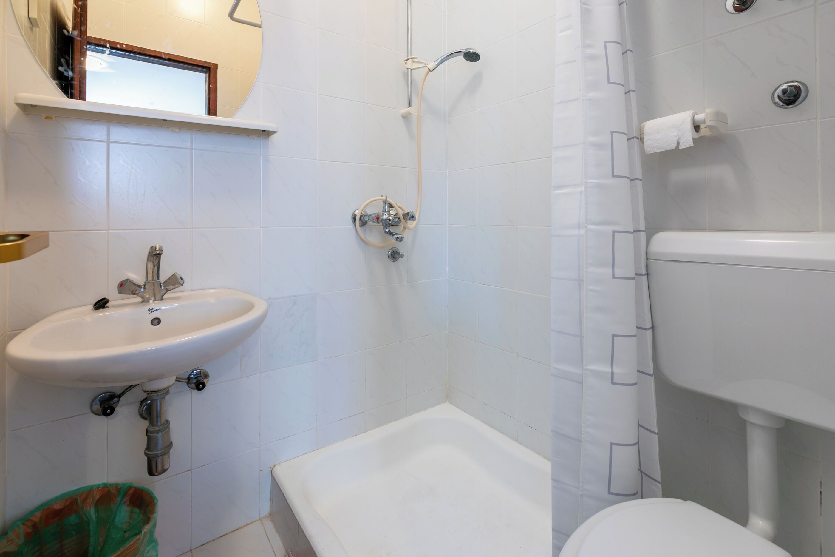 Ein Badezimmer mit Waschbecken, Toilette, Dusche und Spiegel.