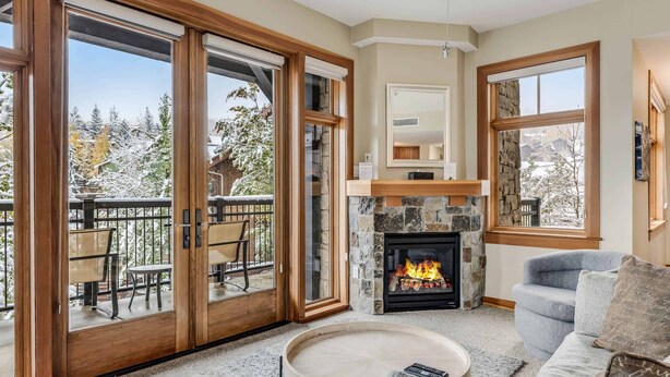 A cozy living room with a stone fireplace, a comfortable sofa, and a dining area with a table and chairs. - Capitol Peak Lodge 3210 (Snowmass Village)