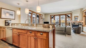 A spacious kitchen with wooden cabinets, a granite countertop, and pendant lighting. - Capitol Peak Lodge 3210 (Snowmass Village)