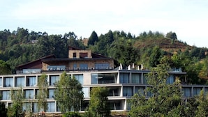 Un edifici modern d'àmbit elevat amb grans finestrals, amb un paisatge de pendent forestal de fons.