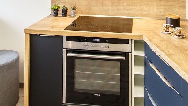 Una cocina moderna con horno empotrado, microondas y campana extractora de acero inoxidable.