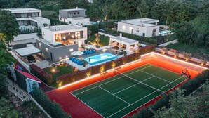 Un complejo residencial moderno con varias casas, una piscina y una cancha de tenis.