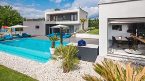 Una casa moderna con piscina, mobiliario exterior y zona de patio.