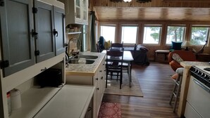 Una cocina compacta con una isla central, armarios de madera y un comedor con mesa y sillas.