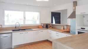 A modern kitchen with white cabinets, a wooden countertop, a built-in oven, and a window providing natural light. - Cozy home in Ginestas with WiFi (Ginestas)