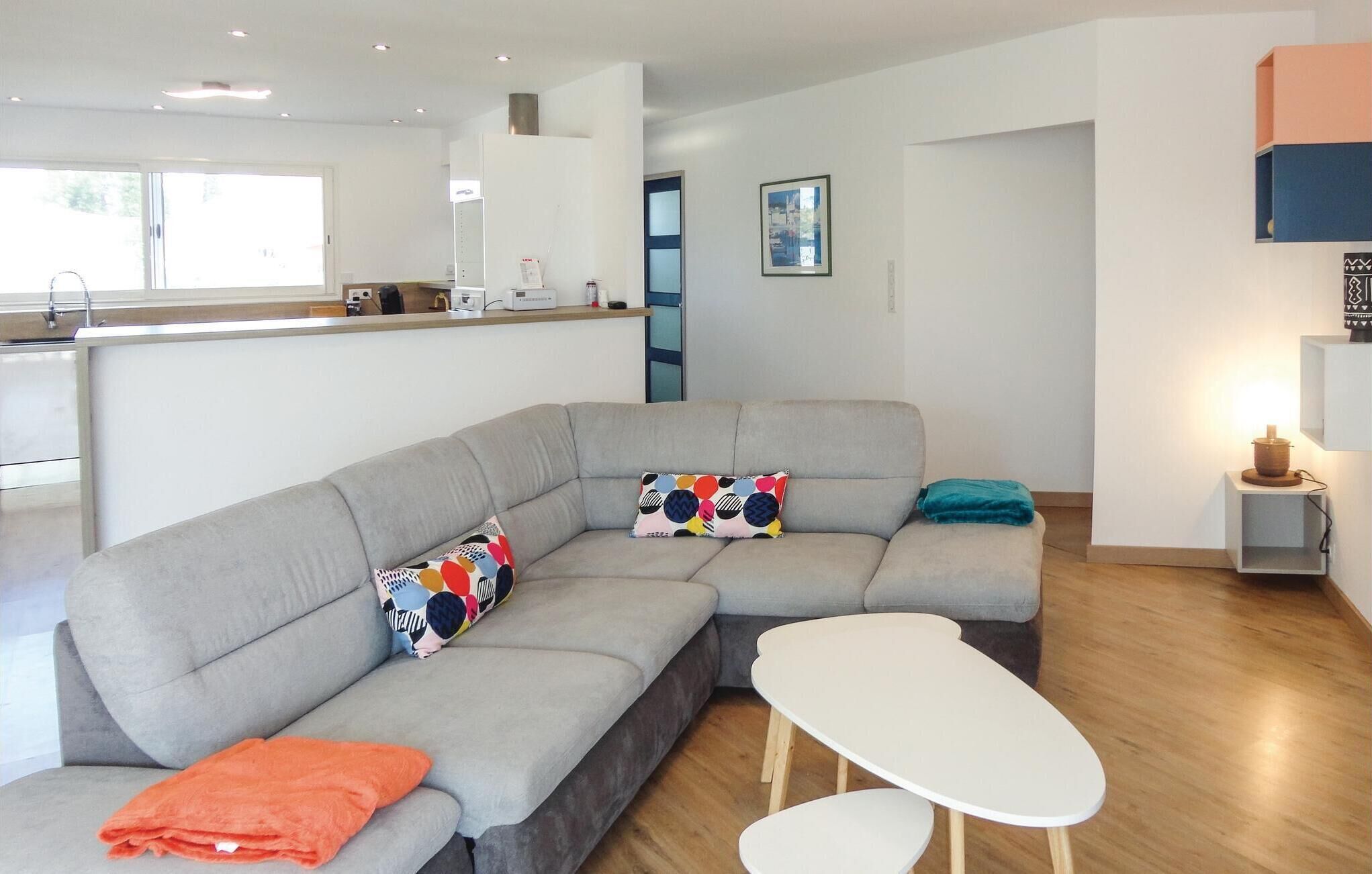 A modern living room with a grey sectional sofa, a white coffee table, and a teal throw pillow.