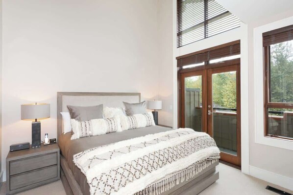 Ein Schlafzimmer mit einem Bett, Nachttischen und einem großen Fenster.