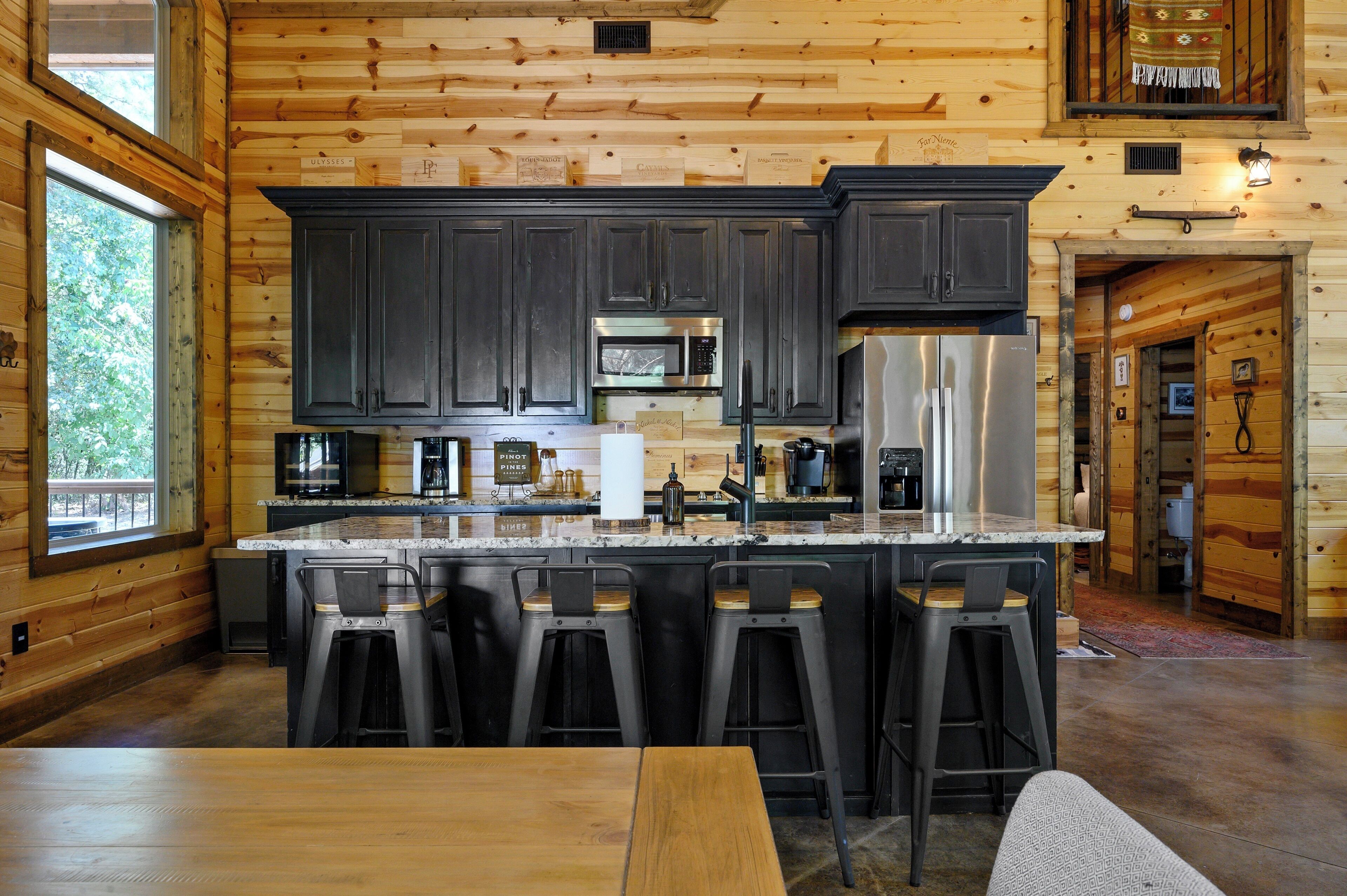 A modern kitchen with dark cabinets, stainless steel appliances, and a central island with bar stools.