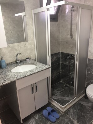 Superior appartement | Badkamer | Een douche, een haardroger, pantoffels, zeep