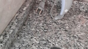 A hairdryer against a tiled wall in a bathroom with a granite countertop. - Celebi Apart Hotel (Izmir)