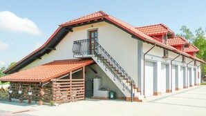 A building with a red-tiled roof, a balcony with black railings, and a staircase leading to the entrance. - Nice apartment in Borcz with kitchen (Borcz)