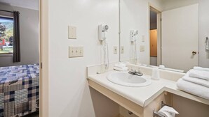 A hotel bathroom with a large mirror, a sink, and a towel rack.