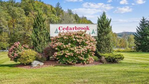 A sign for Cedarbrook with a well-maintained garden and trees in the background.