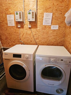 Zwei Waschmaschinen mit Frontlader, eine Steckdose und eine Holzwand.