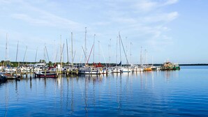 Uma marina com vários barcos atracados, águas calmas e céu claro.