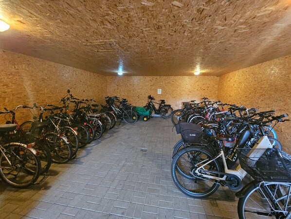 Ein Fahrradabstellbereich mit mehreren FahrrĂ€dern, einem grĂŒnen E-Bike und einem Dreirad.