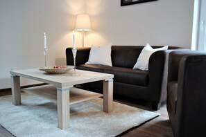 En moderne stue med et træsofabord, en mørkebrun sofa og en hvid måtte.