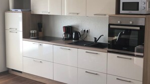 Una cocina moderna con gabinetes blancos, microondas, cafetera y horno.