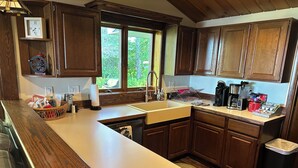 A kitchen with wooden cabinets, a sink, and various appliances. - Freighters in front yard!  Private Sandy Beach - Large Deck - Best View on River (Sault Ste. Marie)