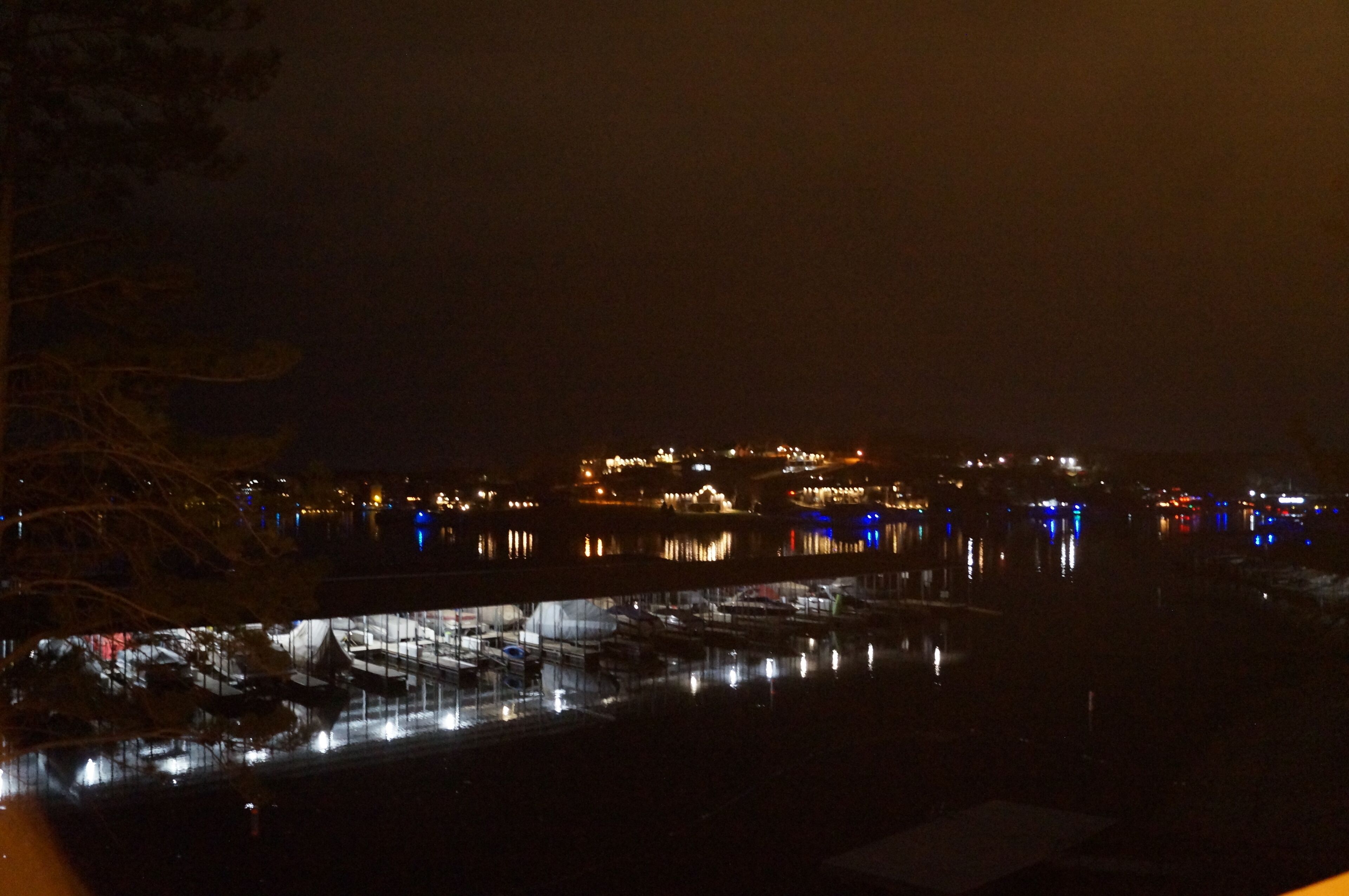 Vista nocturna de una zona costera con edificios y barcos.
