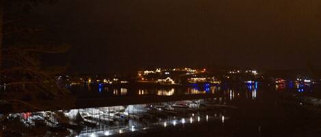 Vista nocturna de una zona costera con edificios y barcos.