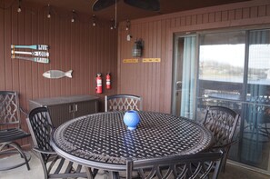 A covered patio with a round metal table and chairs, a fish-shaped sign, and a fire extinguisher.