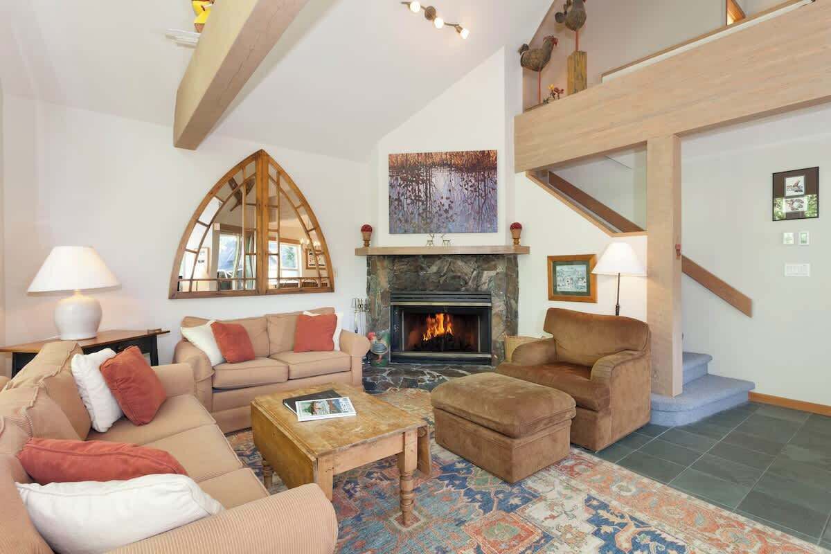 A living room with a fireplace, sofas, a coffee table, and a patterned rug.