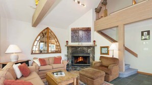 A living room with a fireplace, sofas, a coffee table, and a patterned rug.