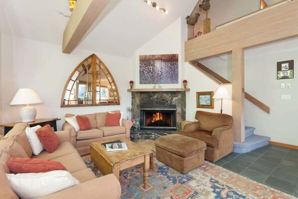 A living room with a fireplace, sofas, a coffee table, and a patterned rug.
