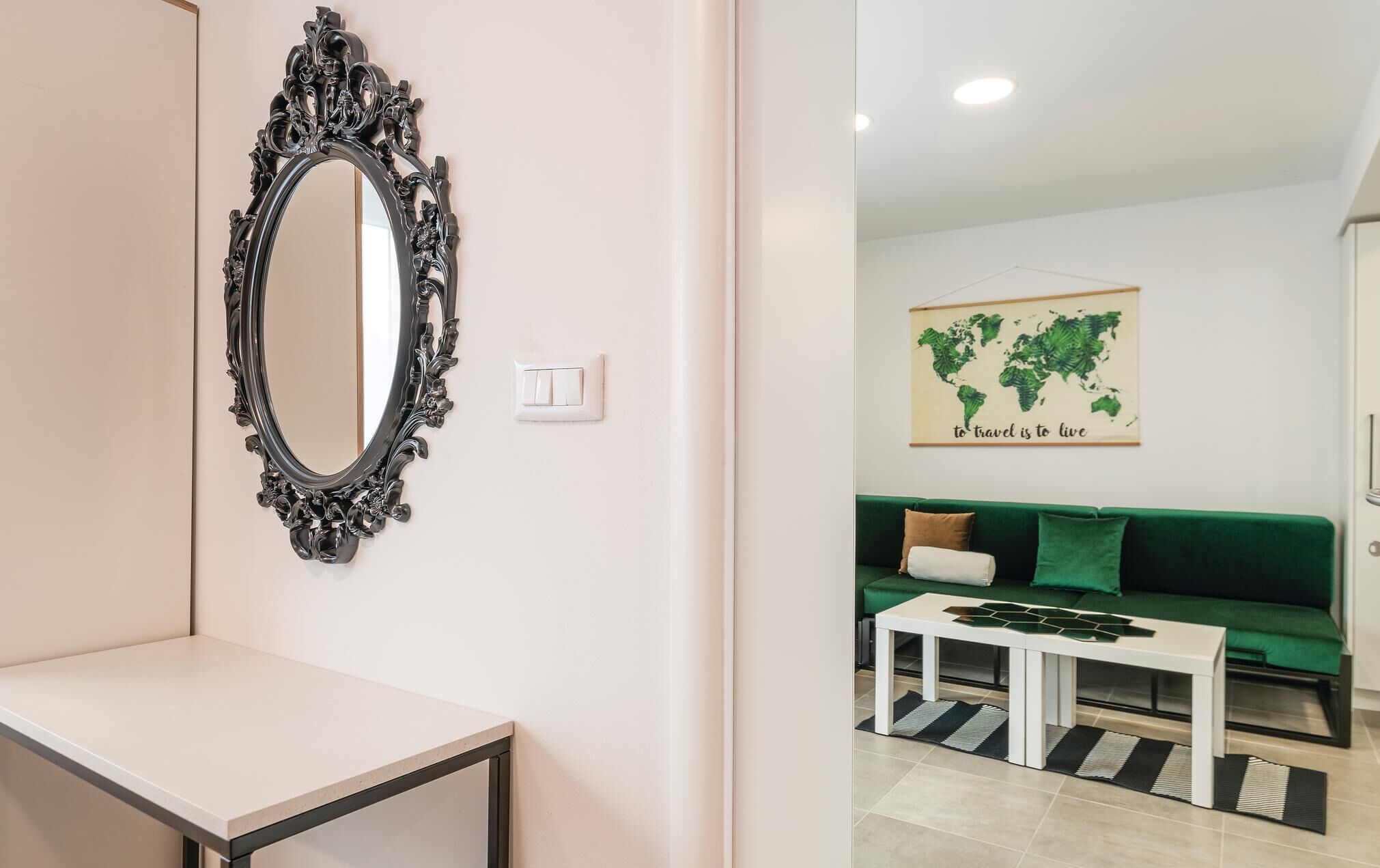 A modern living room with a green sofa, a white coffee table, and a world map artwork on the wall.