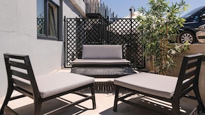A patio with two wooden chairs and a bench, a black metal fence, and a car parked nearby. - Awesome apartment in Fazana with WiFi (Fazana)