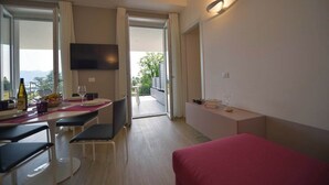 Une chambre d’hôtel moderne dotée d’un balcon, d’un coin repas et d’un téléviseur fixé au mur.